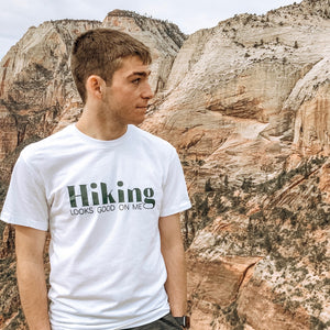 man standing in zion national park wearing a white hiking looks good on me t shirt with green lettering